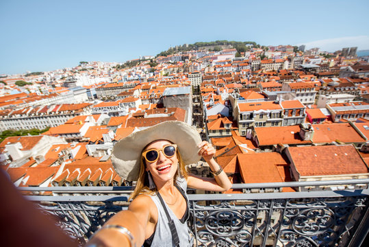 Young woman tourist making selfie photo on the beautiful cityscape top view background in the old town during the sunny day in Lisbon, Portugal