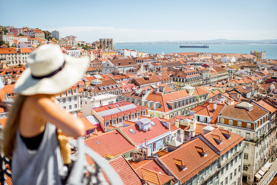 Young woman tourist enjoying beautiful cityscape top view on the old town during the sunny day in Lisbon city, Portugal. Image focused on the background