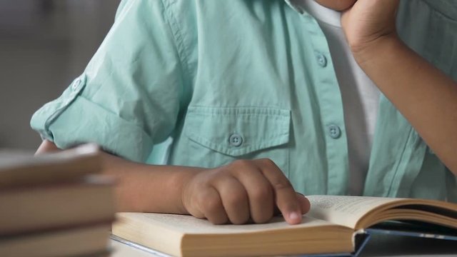 Small child having difficulties with reading book, following lines with finger