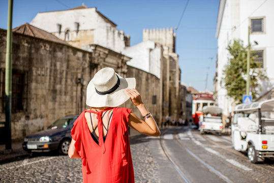 Portrait of a young woman traveler in red dress standing on the street with famous tourist tram on the background in Lisbon, Portugal