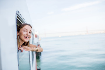 Young woman traveler pulling out face from the window in the water taxi in Lisbon, Portugal