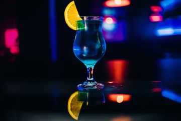 glass of blue alcohol cocktail Martini with a slice of orange party at bar