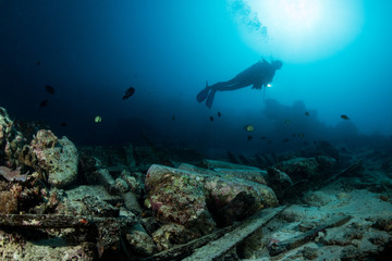 scuba diver over the wooden wreck of a diving boat with tanks in Maratua