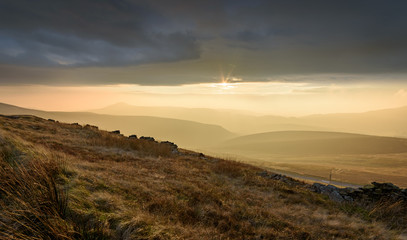 Obraz premium Beautiful autumn scenery in the Peak District - layers of hills and sunlight with dramatic clouds hanging over