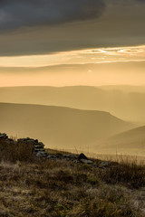 Beautiful autumn scenery in the Peak District - layers of hills and sunlight with dramatic clouds hanging over