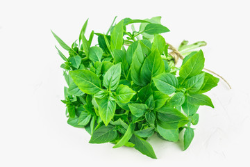 A bunch of green lemon basil on a white concrete table against a brick wall background