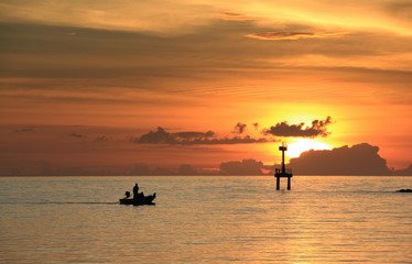 The fisherman drove the boat home through the lighthouse at sunset silhouette