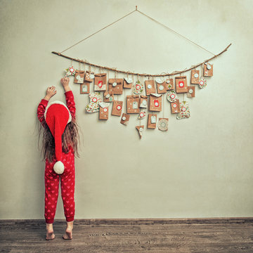 child in pajamas and Christmas cap stretches for advent calendar with small gifts