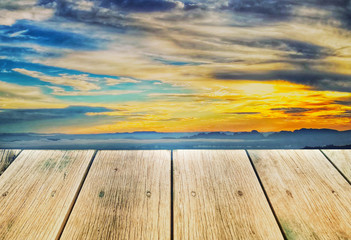 Fototapeta na wymiar Wood board on colorful sunset sky, used for montage or display products among beautiful landscape.