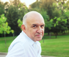 Portrait of friendly smiling senior man at summer evening