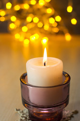 Candle on the background of Christmas lights. Selective focus.
