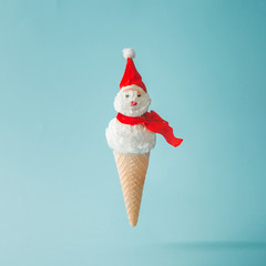 Snowman made of ice cream on bright blue background. Winter holiday concept.