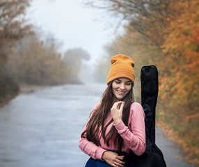 Woman holding a guitar standing on a countryside road