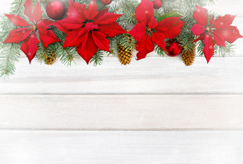 Fototapeta na wymiar Christmas decoration. Flowers of red poinsettia, branch christmas tree, christmas ball and cone spruce on background of white painted wooden planks. Top view, flat lay