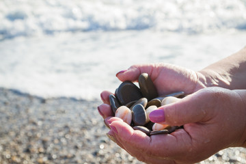 Sea stones in hands on the beach in the summer