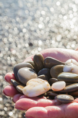 Fototapeta na wymiar Sea stones in hands on the beach in the summer
