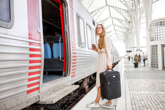 Young and beautiful woman with coffee cup and luggage boarding in the train at the railway station
