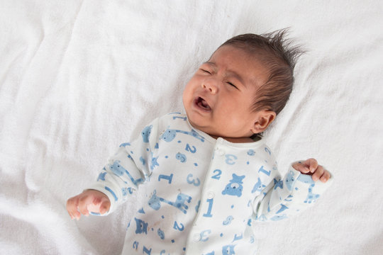 Cute asian newborn crying on white towel