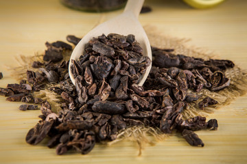 closeup raw cacao beans on big wooden spoon on sackcloth