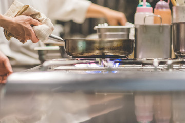 Closeup of Chef in restaurant kitchen at stove with pan.