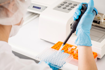 Focused young life researcher with pipette.