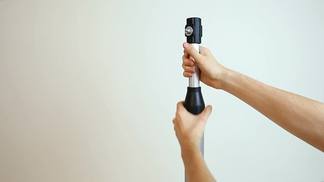Male hands adjusting length of camera monopod, footage stabilization equipment
