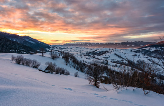 winter dawn in mountainous countryside. gorgeous cloudy sky over the snow covered hills. wide mountain ridge in a far distance