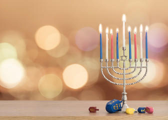 Hanukkah Jewish holiday background with menorah (Judaism candelabra)  burning candles and traditional Dreidrel game toy on wood table and on autumn bokeh sun flare - obrazy, fototapety, plakaty