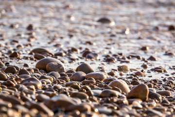 pebbles on the beach and blurred sea wave in the background