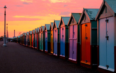 A row of 30 colourful beach beach huts in a line, with a diminishing perspective, all the beach...