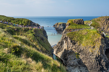 Thousands of tourists visiting Carrick-a-Rede Rope Bridge in County Antrim of Northern Ireland, hanging 30m above rocks and spanning 20m, linking mainland with the tiny island of Carrickarede