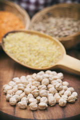 Vertical Shot Of Chickpeas, Red And Green Lentils And A Wooden Scoop Full Of Cracked Wheat