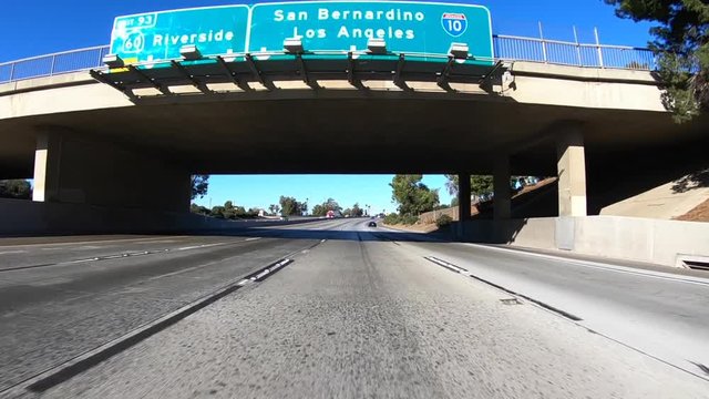San Bernardino and Los Angeles Interstate 10 overhead freeway sign slow motion car mount driving shot.