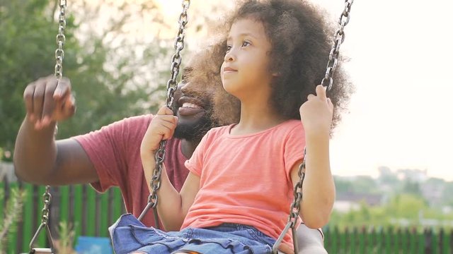 Loving dad swinging his child in yard and pointing upward, family values slow-mo