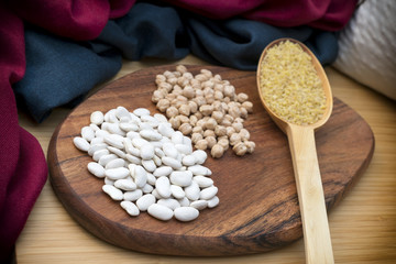 Arrangement Of Dry Beans, Chickpeas And A Wooden Scoop Full Of Cracked Wheat On A Wooden Surface