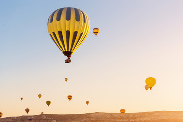 Obraz premium Many hot air balloons flying over rock landscape at Cappadocia at sunrise in early morning