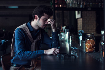 So tired today. Handsome young man looking tired and exhausted while sitting in loft interior at bar counter