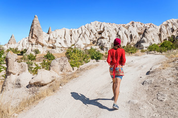 A happy young tourist eastern asian girl in traditional clothes travels among cappadocia landscape and cave towns at summer