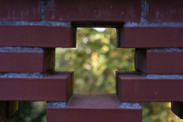 red brick wall see through with cross and garden background