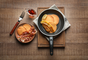 Tasty pancakes with bacon and banana on table