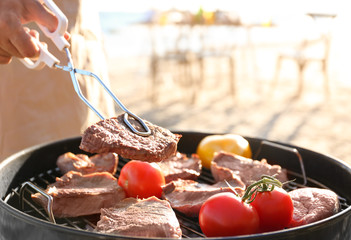 Man cooking steaks and vegetables on barbecue grill, outdoors
