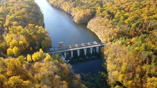 Aerial view of the dam on river with trees covered yellow foliage