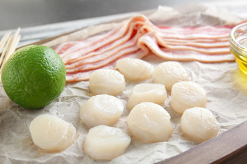 Wooden board with raw bacon and scallops, closeup
