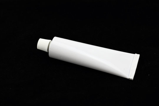 tubo de aluminio esmaltado en blanco en fondo negro para industria de belleza o farmaceútica