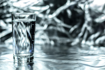 Glass of water on silver abstract background