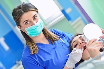 people, medicine, stomatology and health care concept - happy female dentist checking patient girl teeth