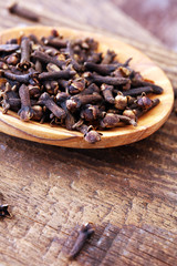 Many Dry cloves spice on brown wooden spoon.