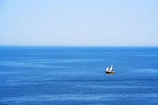 Beautiful calm morning sea summer landscape with a lone sailboat. Minimalism. Ideal background for tourism advertising