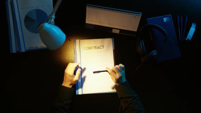 A man is sitting at an office desk and using a phone.