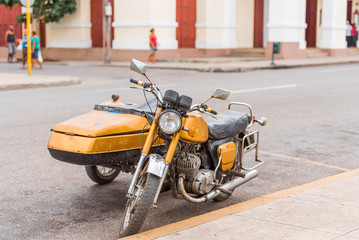 Yellow retro motorcycle on city street, Cuba, Havana. Copy space for text.